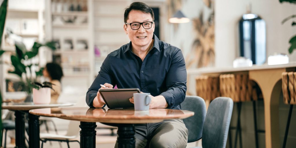 a guy sitting on chair and resting hands on table holding tablet screen