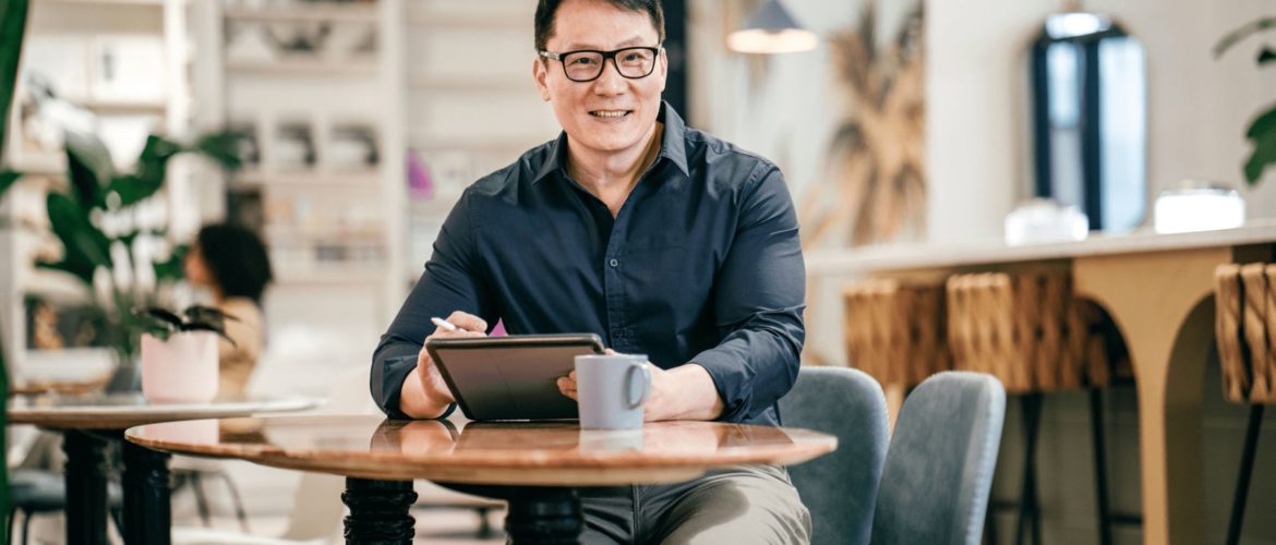 a guy sitting on chair and resting hands on table holding tablet screen