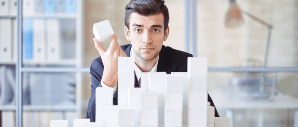 a guy holding a white cube sitting behind white cubes